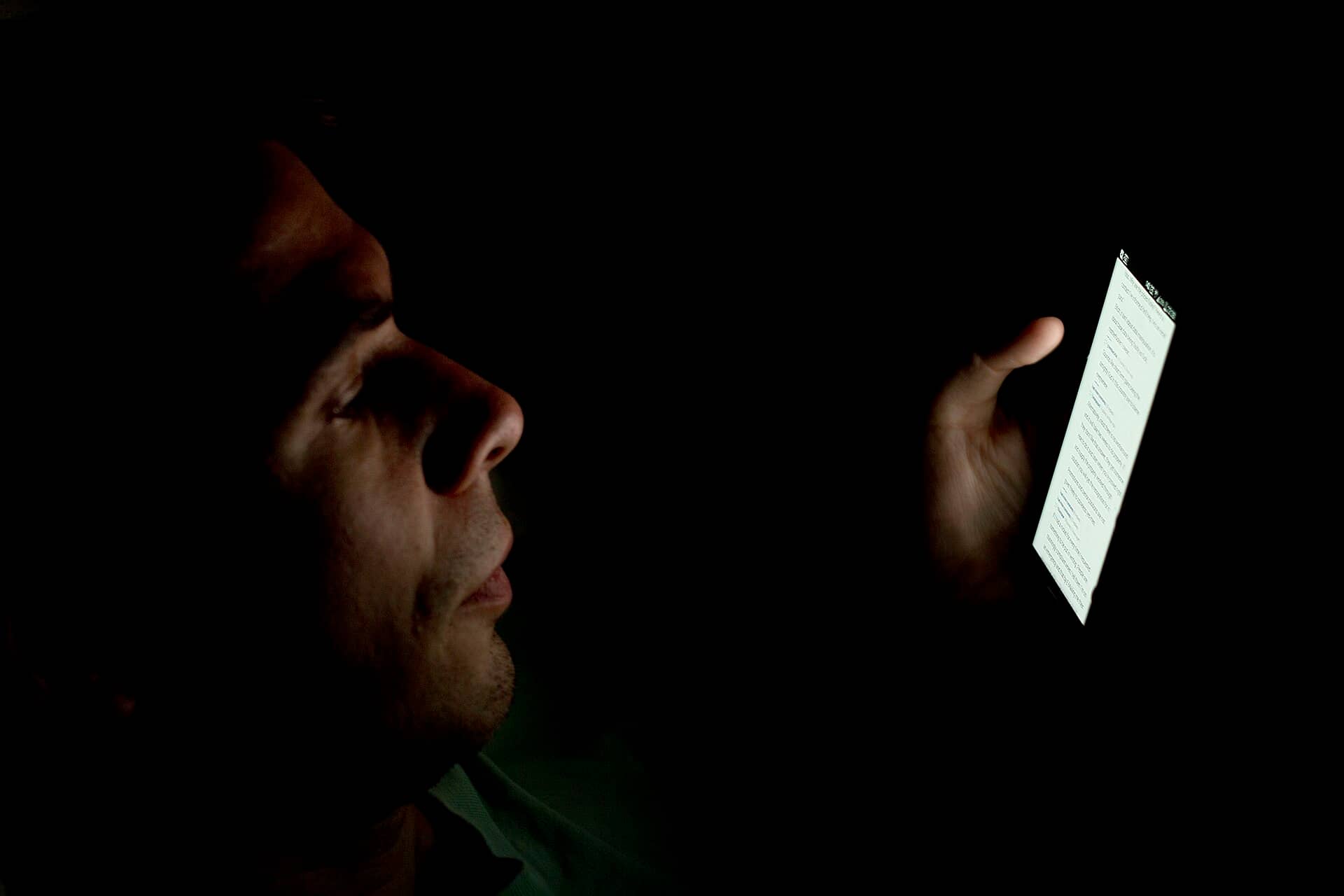 Pessoa olhando a tela do celular em um ambiente escuro