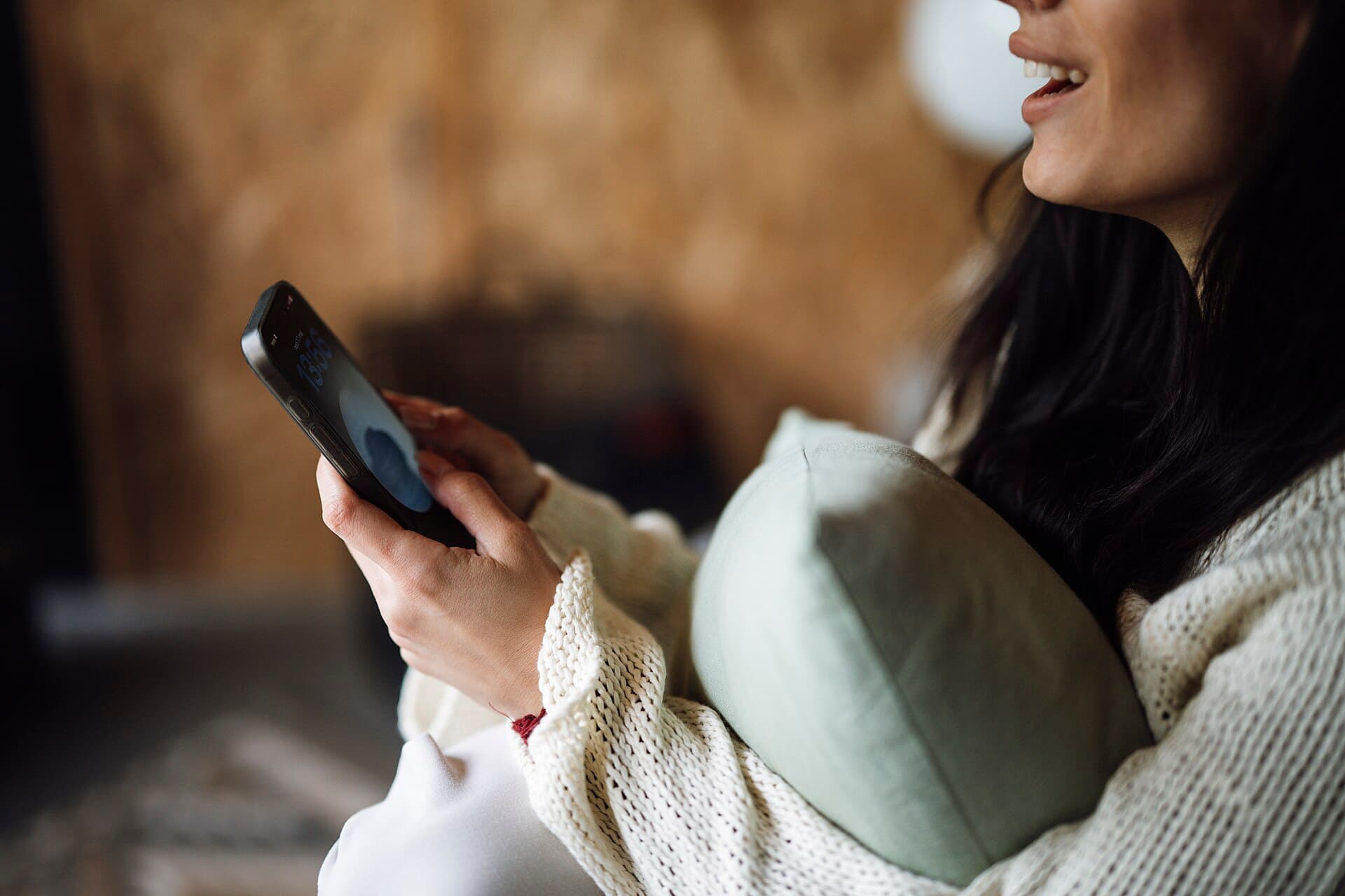 Mulher sentada no sofá olha com atenção a tela do celular